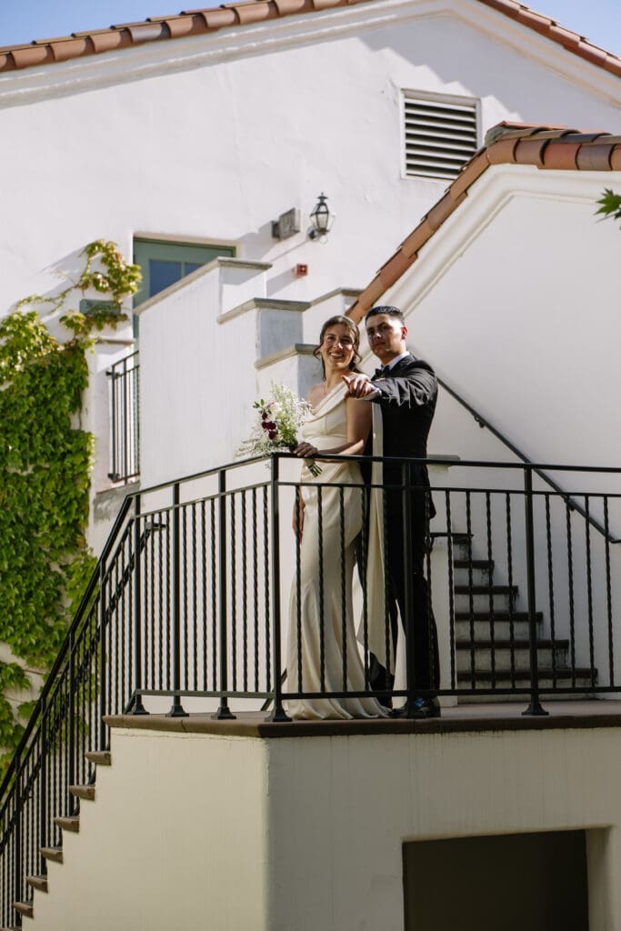 Bride and groom on a staircase, groom pointing out.