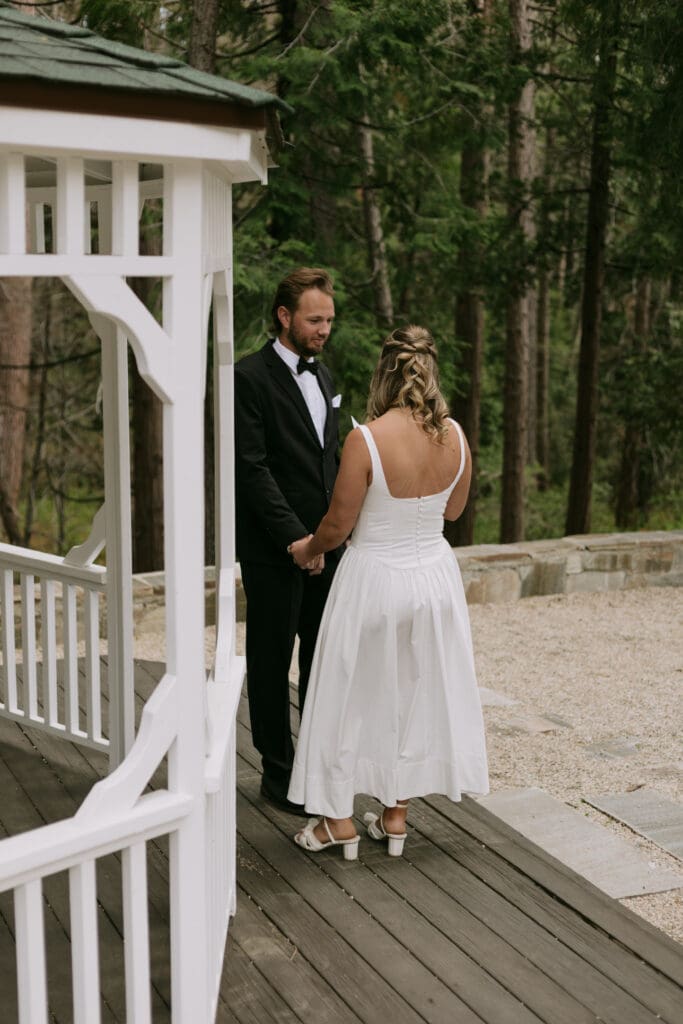 Bride and groom standing in front of a gazebo exchanging vows.