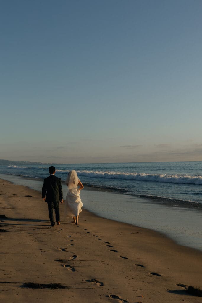 Bride and groom running on the beach at sunset during their beach elopement.