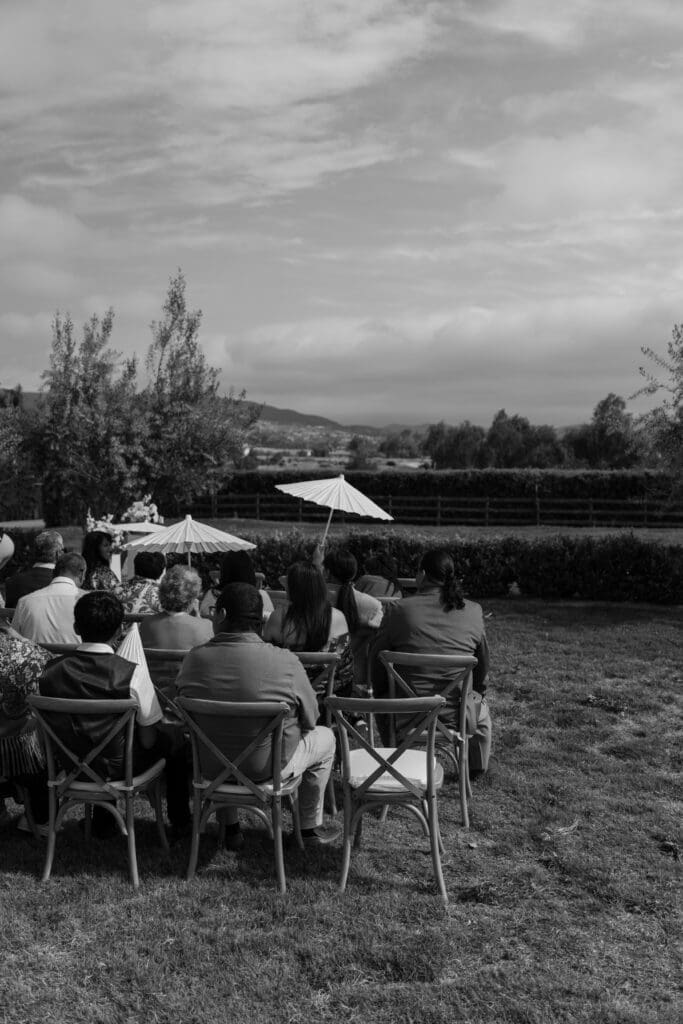 Guests sitting in their seats awaiting the start of the ceremony, in black and white.