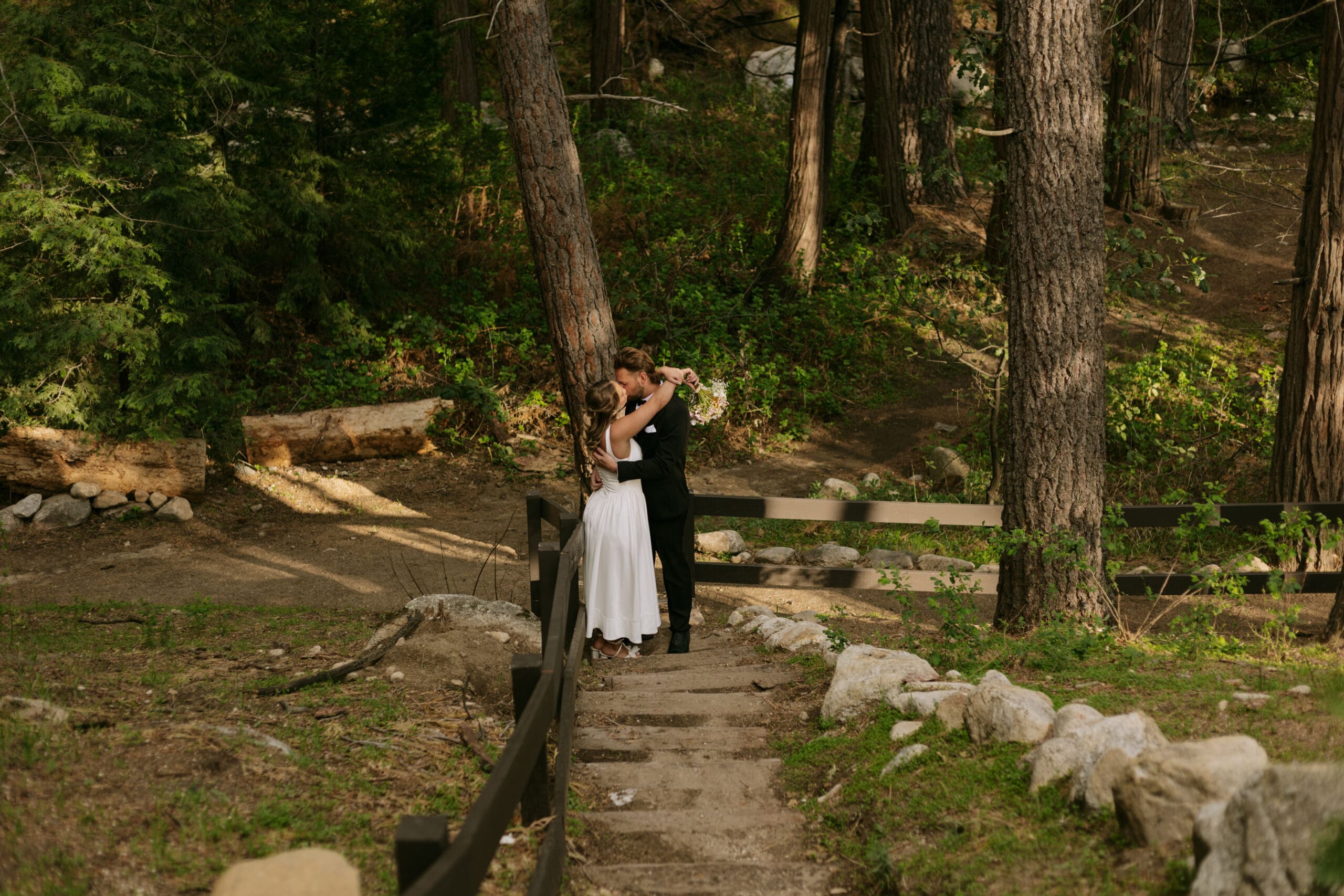 Bride and groom kissing at the bottom of stairs in the mountains.